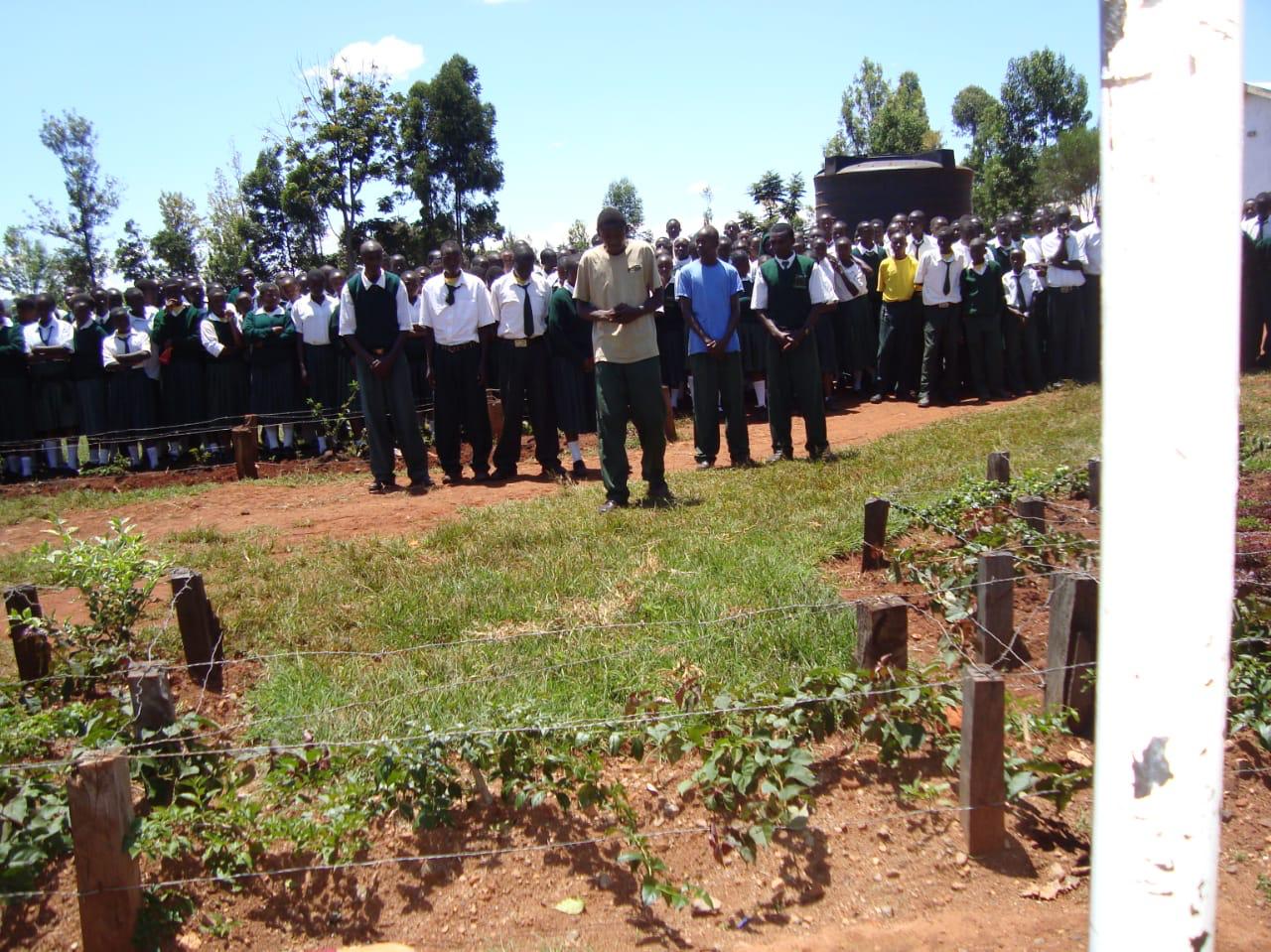 Students gathered outdoors near a garden plot at a school/community event